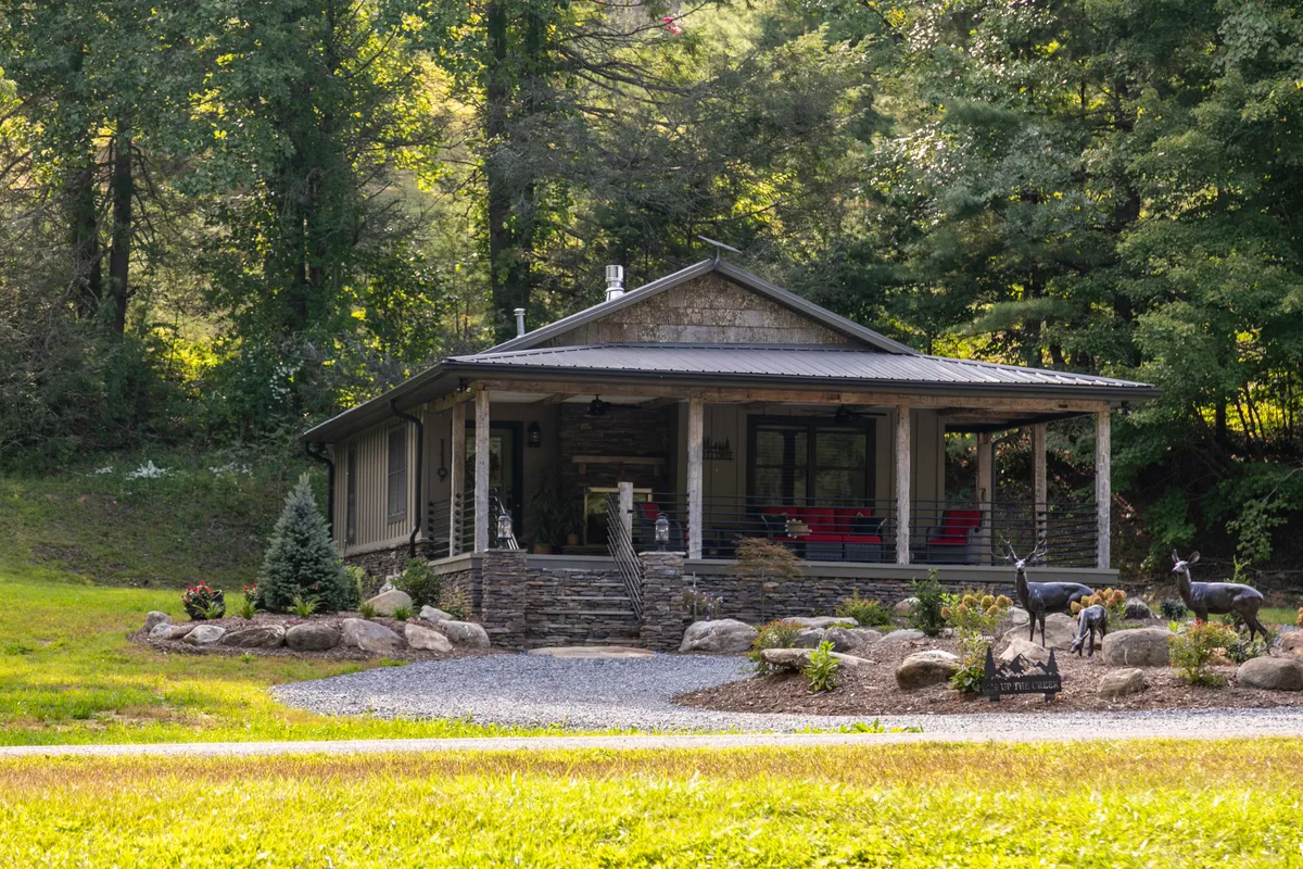 This image features the inviting front porch of the home with a stone facade, surrounded by lush greenery and decorative deer sculptures. The porch offers ample space for gatherings and relaxation, embodying the welcoming outdoor atmosphere highlighted in the section.